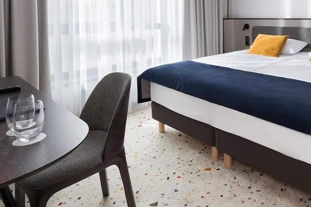 A hotel room with a bed, a desk, and a chair.