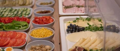 A buffet table with various food items including vegetables, fruits, cheeses, and meats.