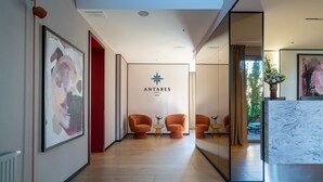 Un moderno vestíbulo de hotel con un área de estar central, un mostrador de recepción y un gran cartel en la pared.