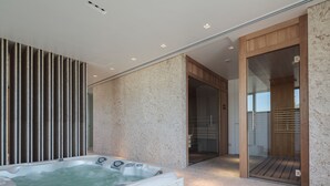 Een moderne badkamer met een marmeren wand, een vrijstaand bad en een houten deur naar een douchegedeelte.