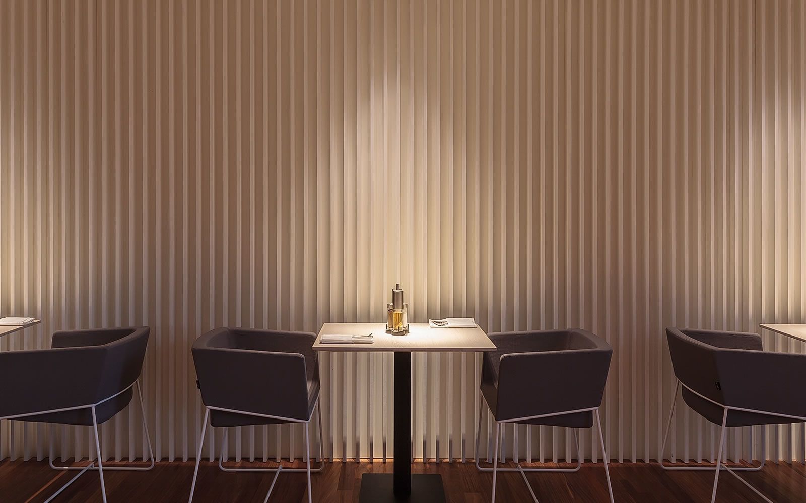 Un espace repas moderne avec une table centrale et quatre chaises, encadré de stores verticaux.