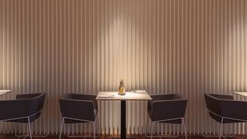 Un espace repas moderne avec une table centrale et quatre chaises, encadré de stores verticaux.