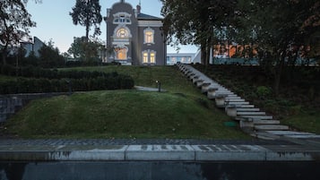 A large, historic building with a symmetrical facade, a central entrance, and a staircase leading up to the main entrance.
