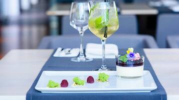 A dining table with a dessert plate, a glass of a light-colored beverage, and a glass of a darker beverage.