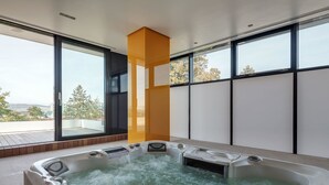A modern spa area with a hot tub, large windows, and a view of the outdoors. - Villa Csonka by Hotel Privo (Targu Mures)