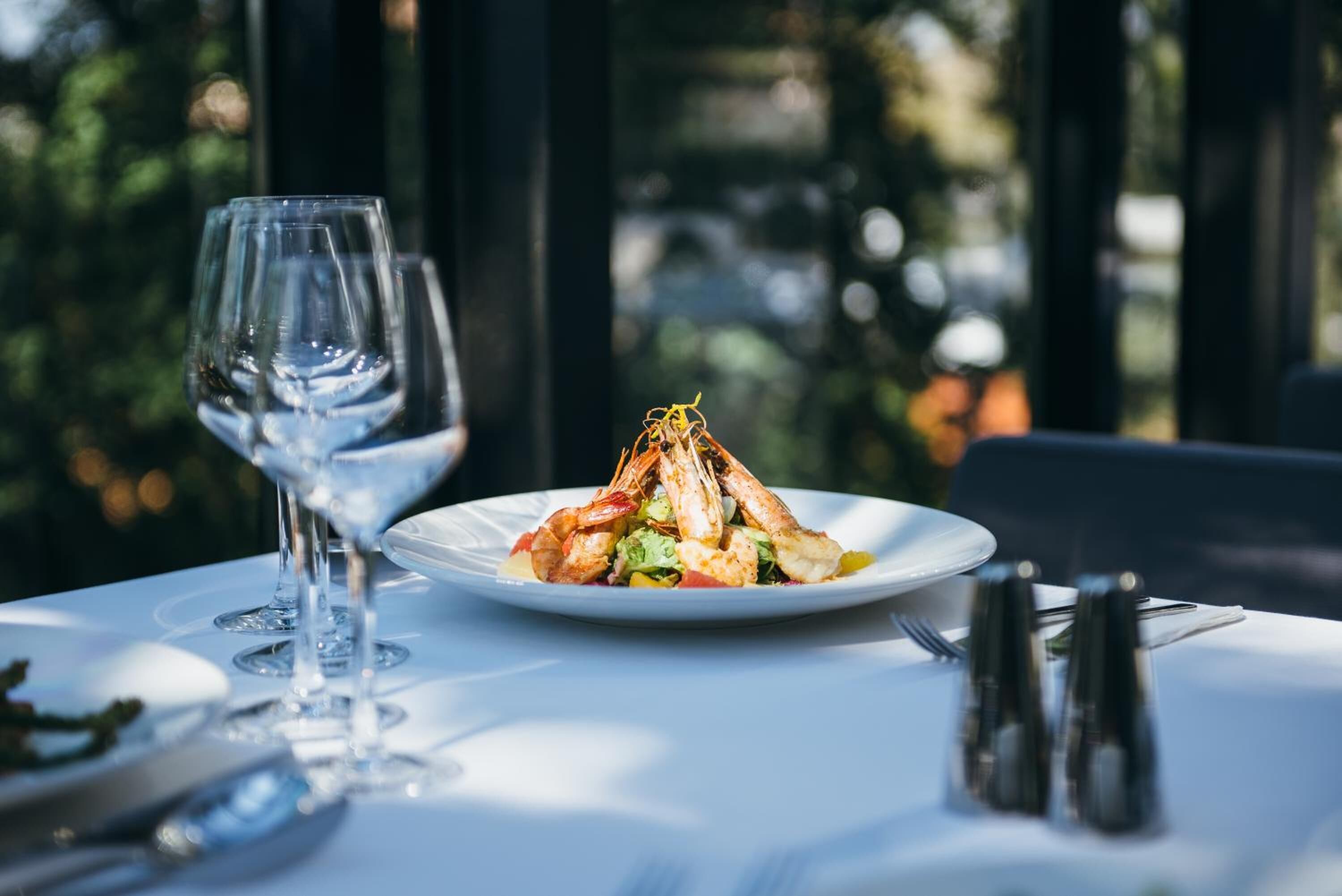 A dining table with a plate of food and a wine glass.