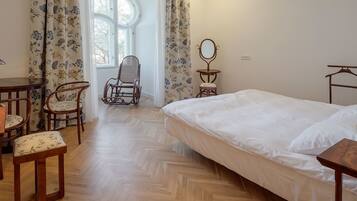 A bedroom with a bed, a chair, a small table, and a mirror.