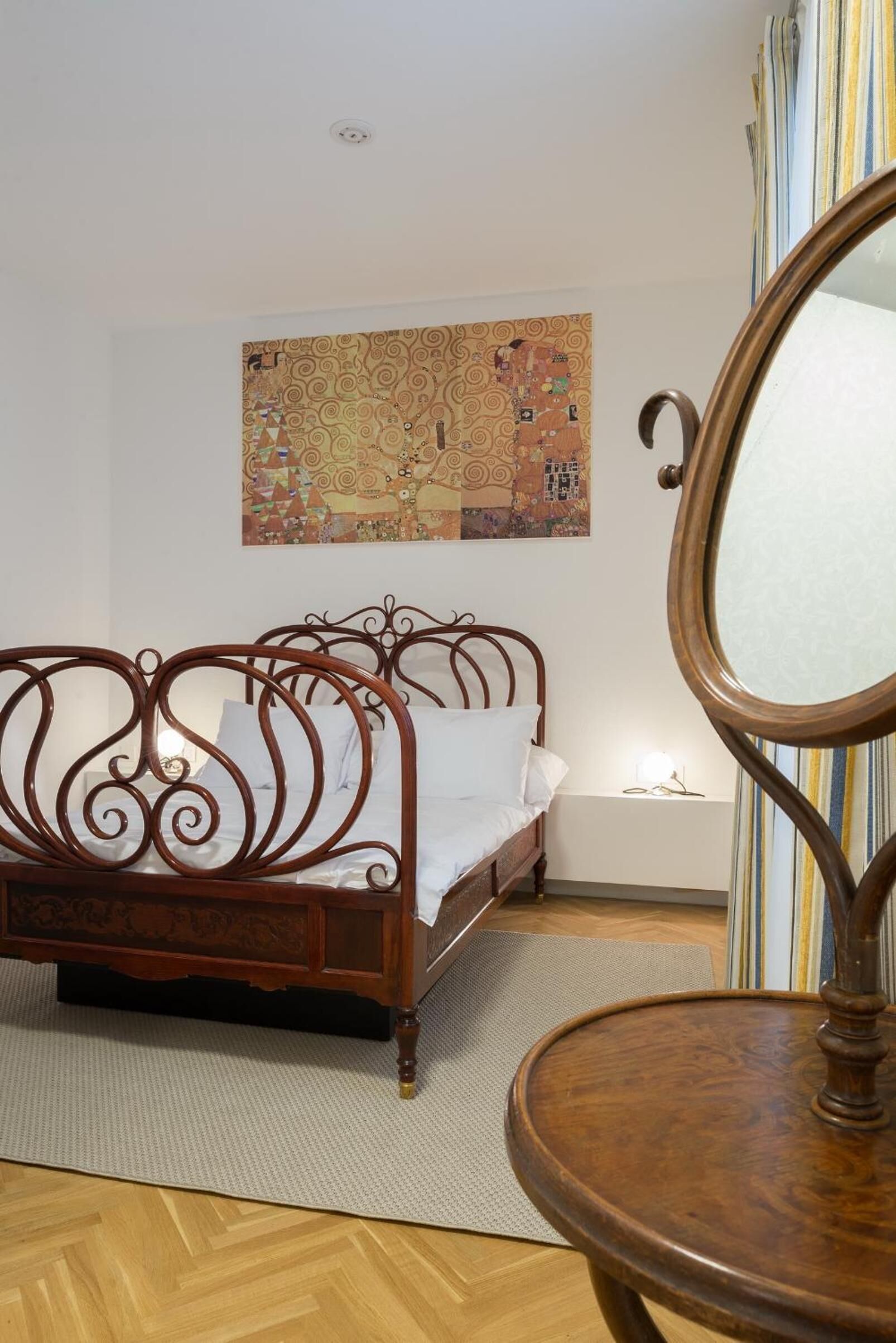 A bedroom with a wooden bed, a large mirror, and a colorful abstract painting on the wall.