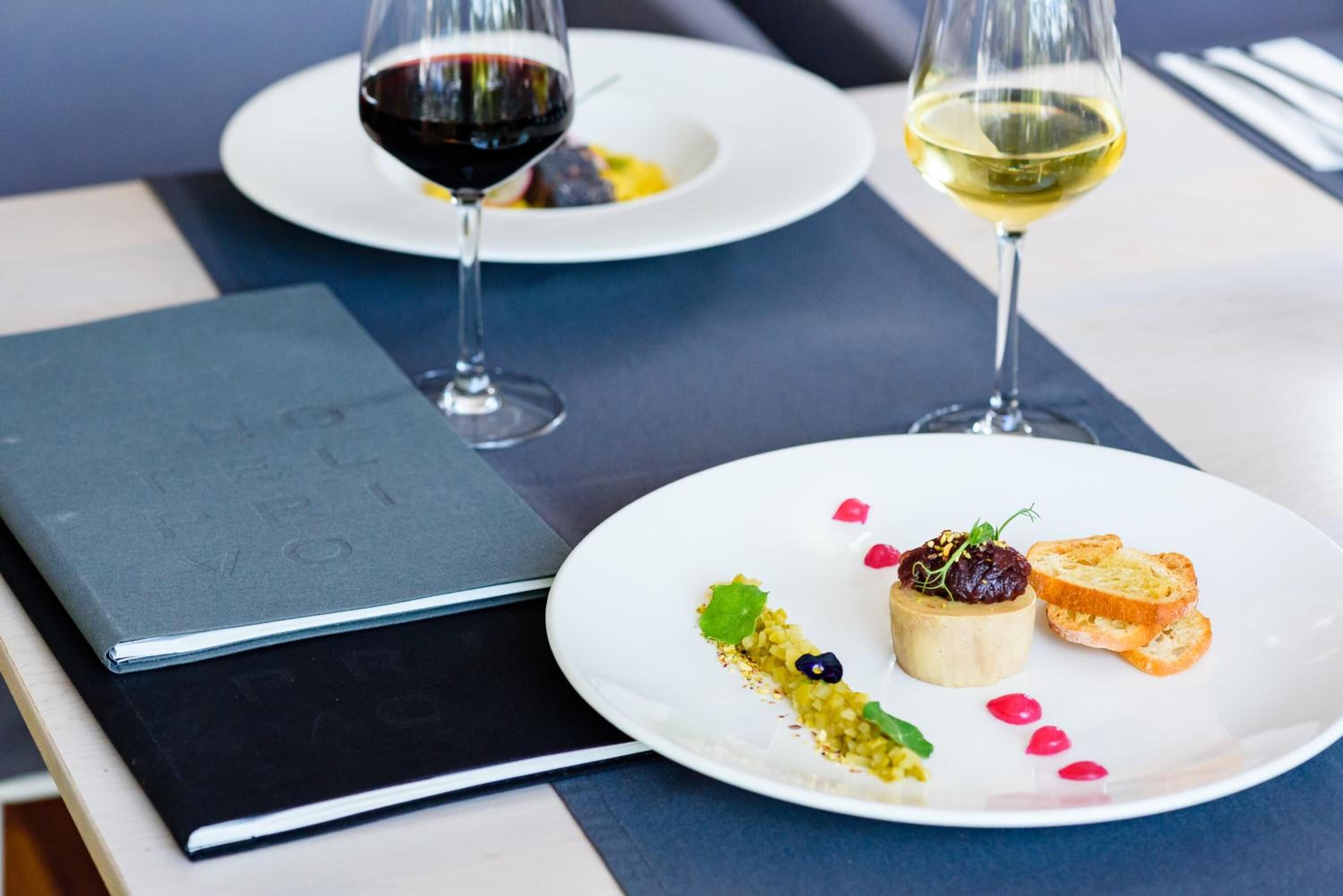 Una mesa con dos platos de comida, cada uno acompañado de una copa de vino.