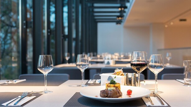 A dining table with a plate of food, wine glasses, and cutlery. - Villa Csonka by Hotel Privo (Targu Mures)