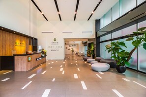 A hotel reception area with a wooden reception desk, a sign reading "Wholesome Hotel," and a modern interior design with a tiled floor and seating area. - Wholesome Hotel  (Taipei)