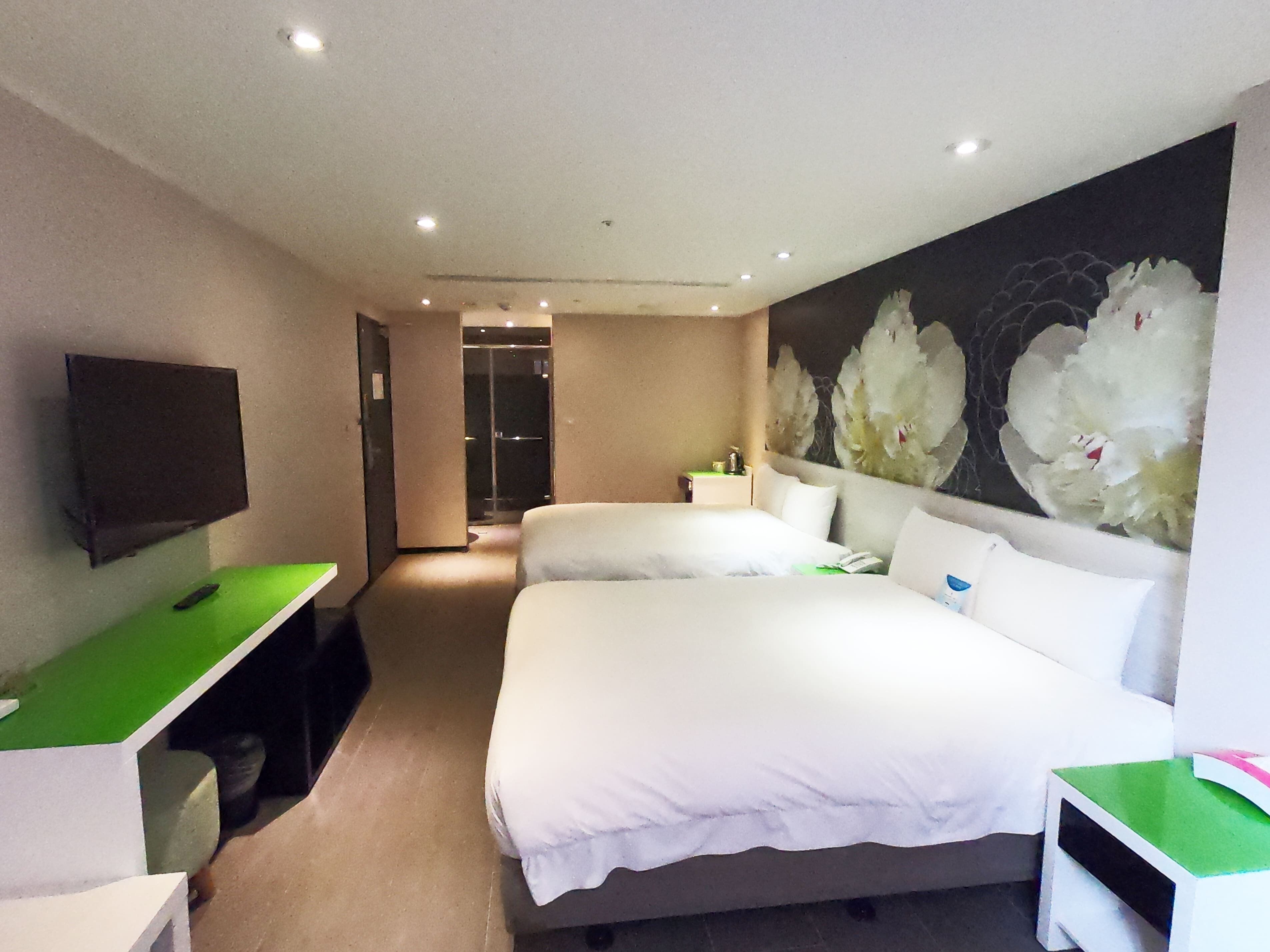 Habitación de hotel con una cama grande, un escritorio, un televisor de pantalla plana y un cuadro de flores en la pared.