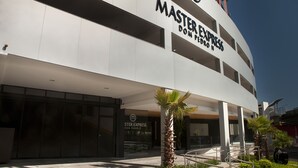 A modern hotel with a prominent 'Master Express' sign, featuring a sleek design with large windows and a palm tree in the foreground. - Master Express Dom Pedro II (Porto Alegre)