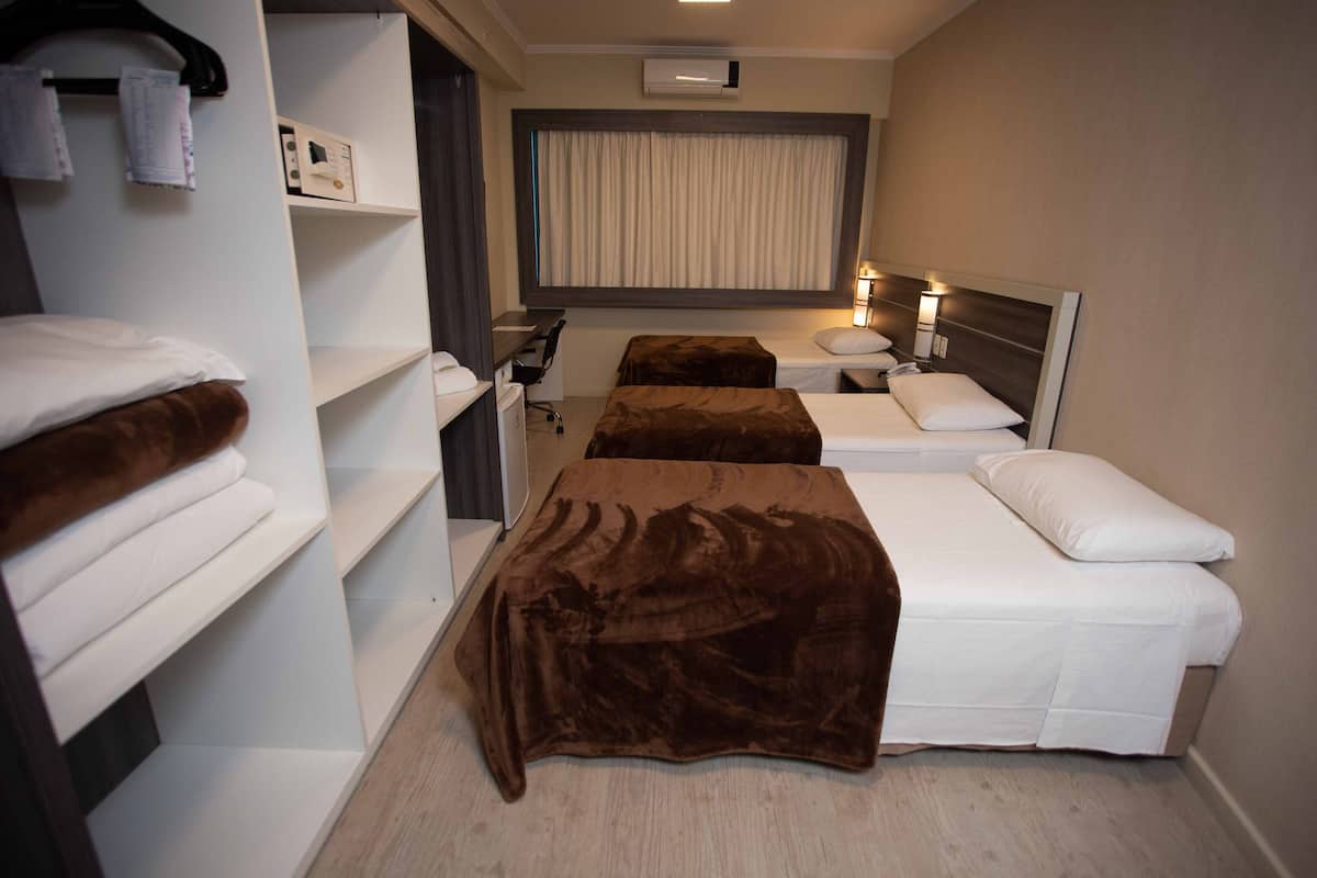 Habitación de hotel con dos camas, un escritorio, una silla y un armario.
