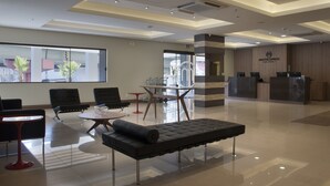 A modern hotel lobby with a reception desk, seating area, and large windows. - Master Express Dom Pedro II (Porto Alegre)