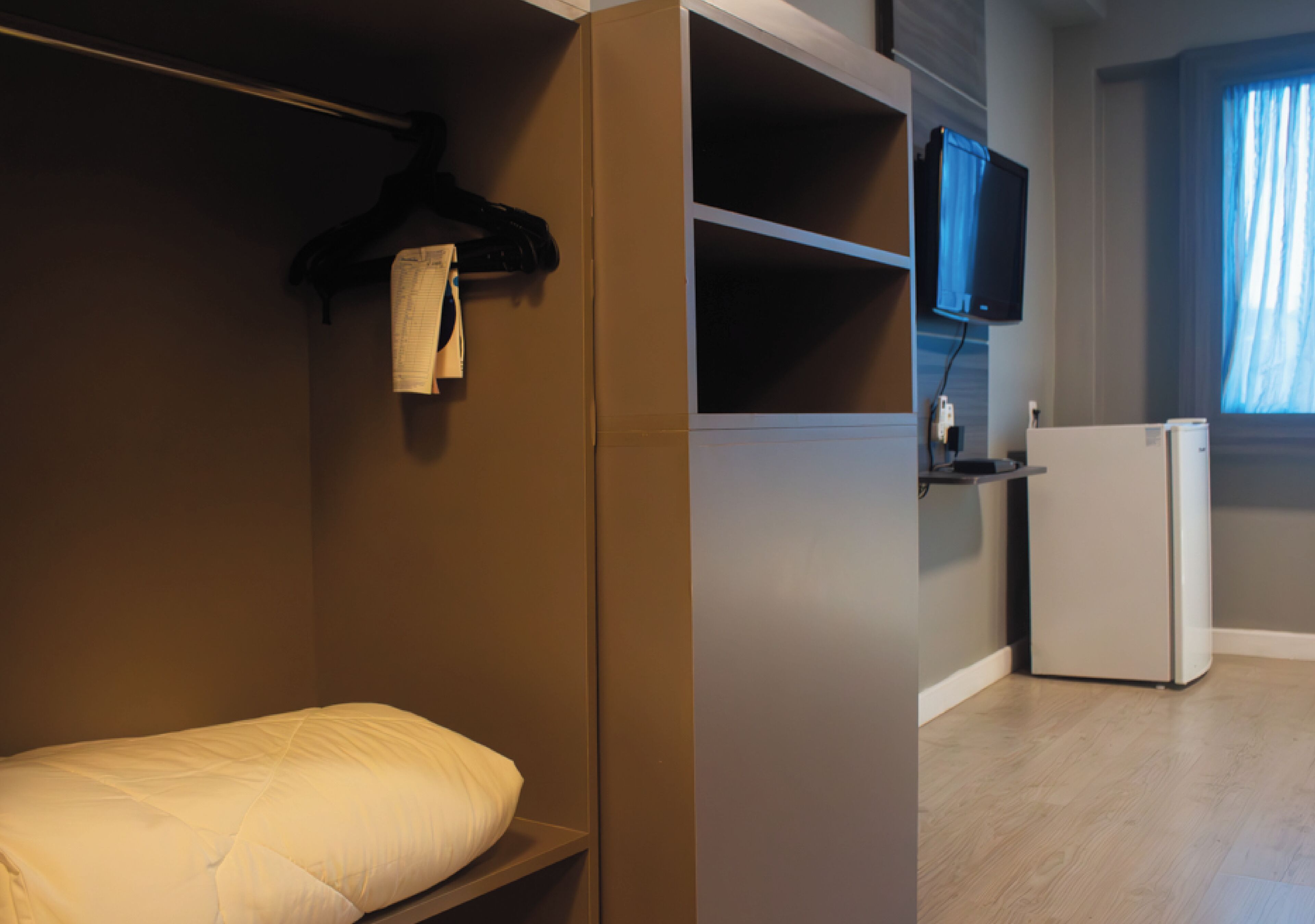 A bedroom with a bed, a wardrobe, a television, and a refrigerator.