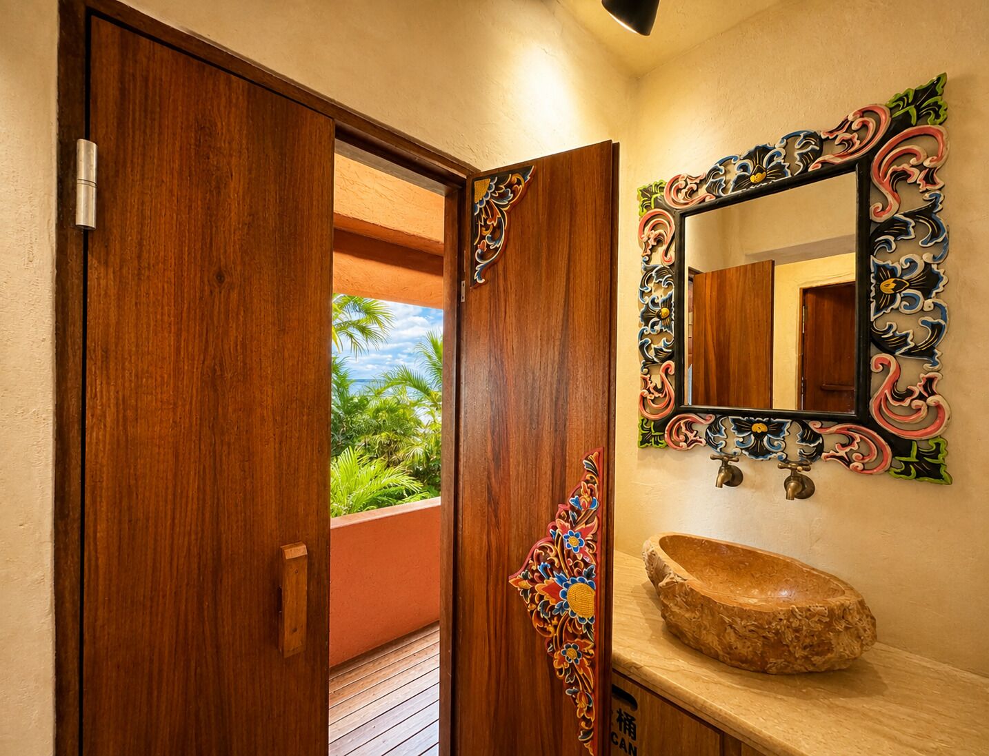 A wooden door leading to a balcony with a view of greenery and a clear sky.