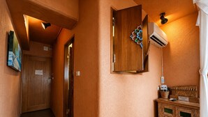 A hallway with a wooden door, a wall-mounted air conditioning unit, and a reception desk with a basket and a sign. - 墾丁阿飛衝浪旅店 Afei Surf Inn - 步行南灣五分鐘 5 Min Walk from South Beach (Hengchun)