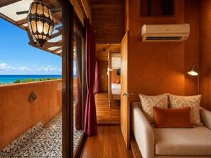 A room with a wooden ceiling, a bed with a white headboard, a sofa with patterned cushions, a red curtain, and a view of the ocean. - 墾丁阿飛衝浪旅店 Afei Surf Inn - 步行南灣五分鐘 5 Min Walk from South Beach (Hengchun)