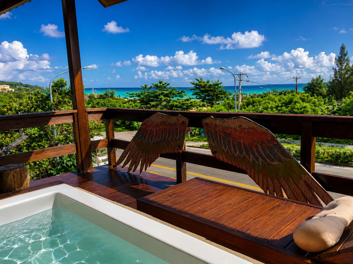 A wooden deck with a pool, benches, and a view of the ocean.