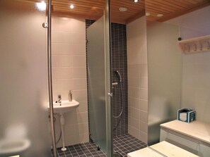 A modern bathroom with a glass-enclosed shower, a white sink, and a toilet.