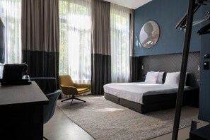 A modern hotel room with a bed, a desk, a chair, and large windows with curtains. - Boutique Hotel Oosteinde (Amsterdam)