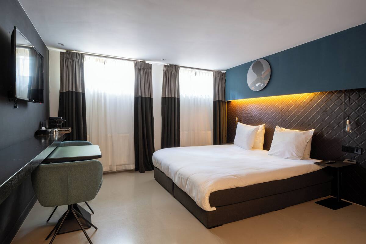 Una habitación de hotel moderna con una cama grande, un escritorio y una silla.