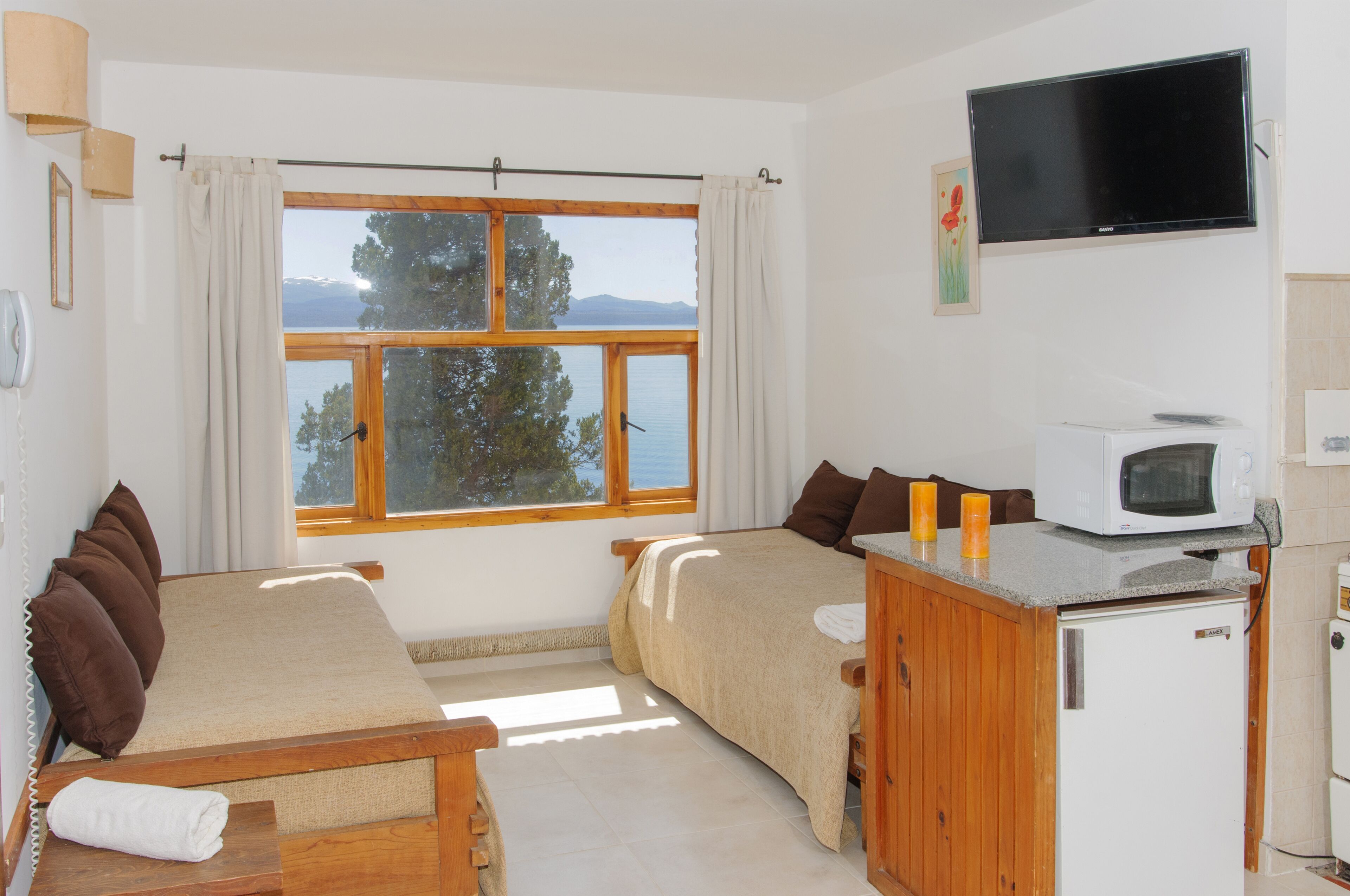 Un dormitorio con dos camas, televisión, microondas y vistas al exterior.