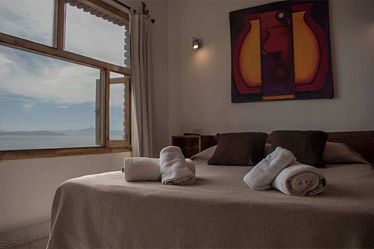 Une chambre d’hôtel avec un lit, des serviettes, un tableau et une vue sur la mer.