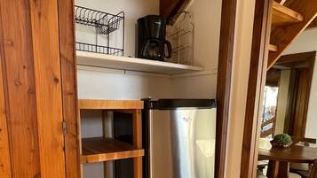 A kitchen with wooden cabinets, a stainless steel refrigerator, and a coffee maker on a shelf.