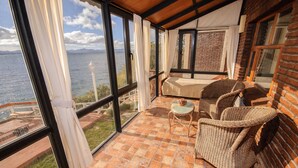 Un balcon avec des meubles en osier, une vue sur la mer et un mur en briques.