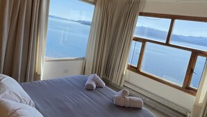 Une chambre à coucher avec un lit, des rideaux et une vue sur la mer.