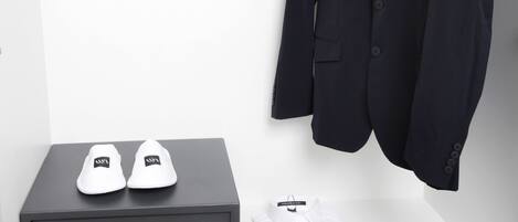 A neatly organized closet with a hanging coat rack, a pair of shoes on a shelf, and a shoe box.