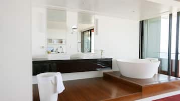 Un baño moderno con una bañera independiente grande, un tocador blanco y un espejo amplio.