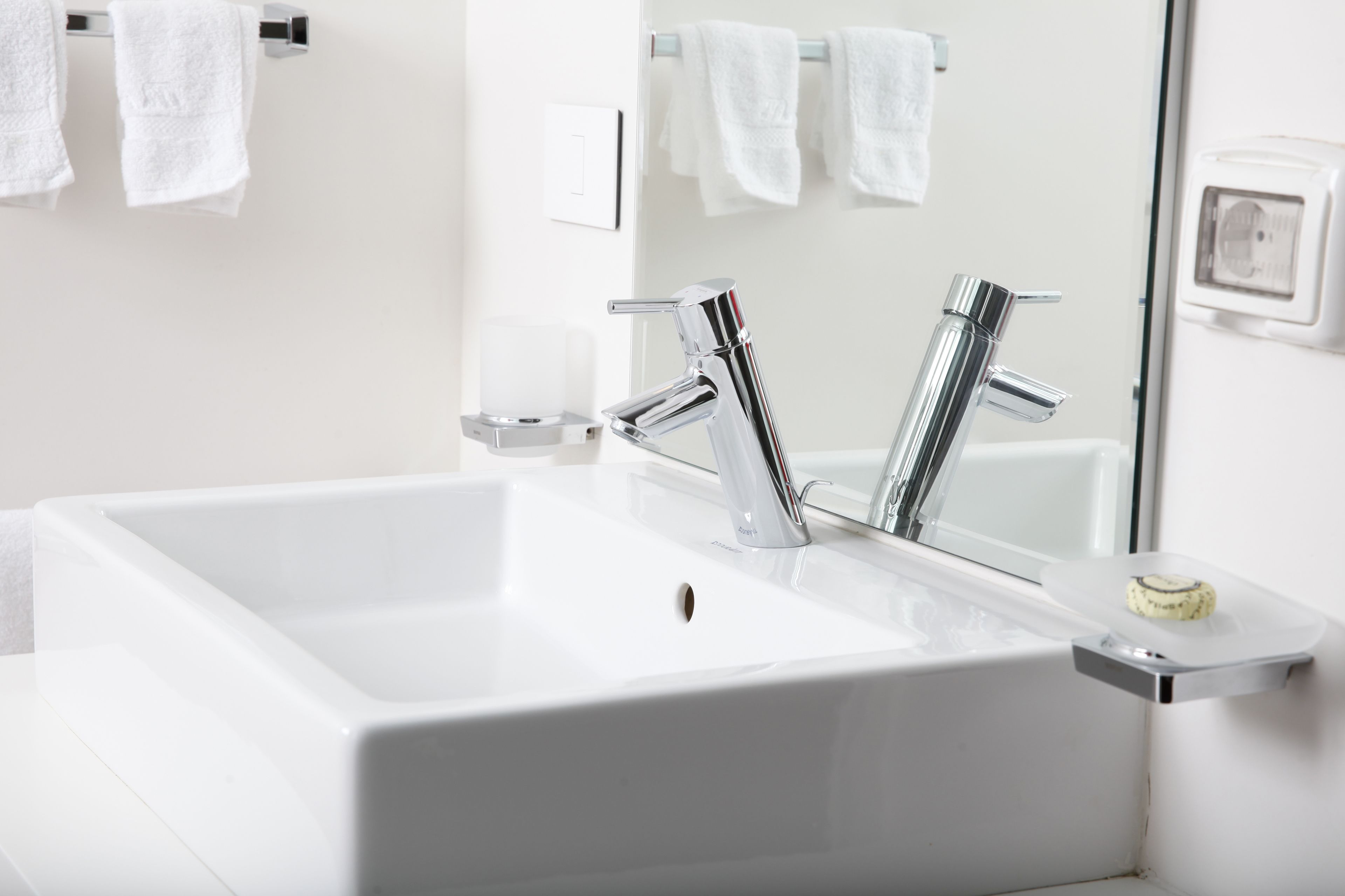A modern bathroom with a white sink, chrome faucet, and a mirror.