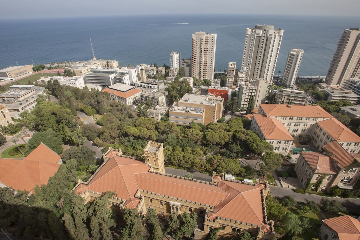 Vista aérea de una ciudad costera con edificios altos, una combinación de estructuras residenciales y comerciales, y una extensa masa de agua al fondo.