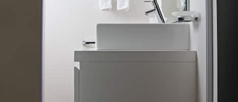 A modern bathroom with a white sink, a mirror, and a towel rack.