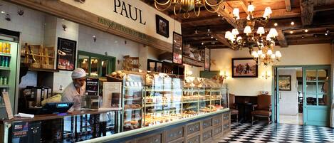 Una panadería con piso de tablones y un letrero que dice 'PAUL'.