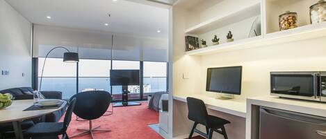 A modern office space with a desk, chairs, a computer, and a refrigerator.