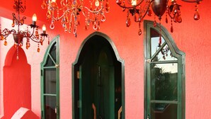 A hallway with a red wall, green doorways, and a chandelier. - Afei Surf Inn - Hall 3 (Hengchun)