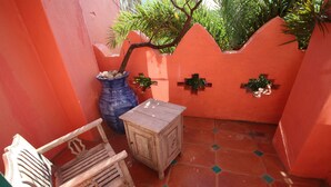 A small, enclosed patio area with a tiled floor, a wooden bench, a small table, and a blue vase with decorative items. - Afei Surf Inn - Hall 3 (Hengchun)