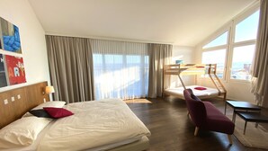 A hotel room with a large bed, a desk, a chair, and a bunk bed. - Businesshotel LUX (Emmen)