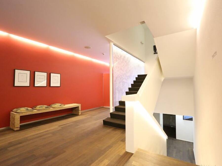 A modern interior with a wooden bench, a staircase, and framed artwork on the wall.