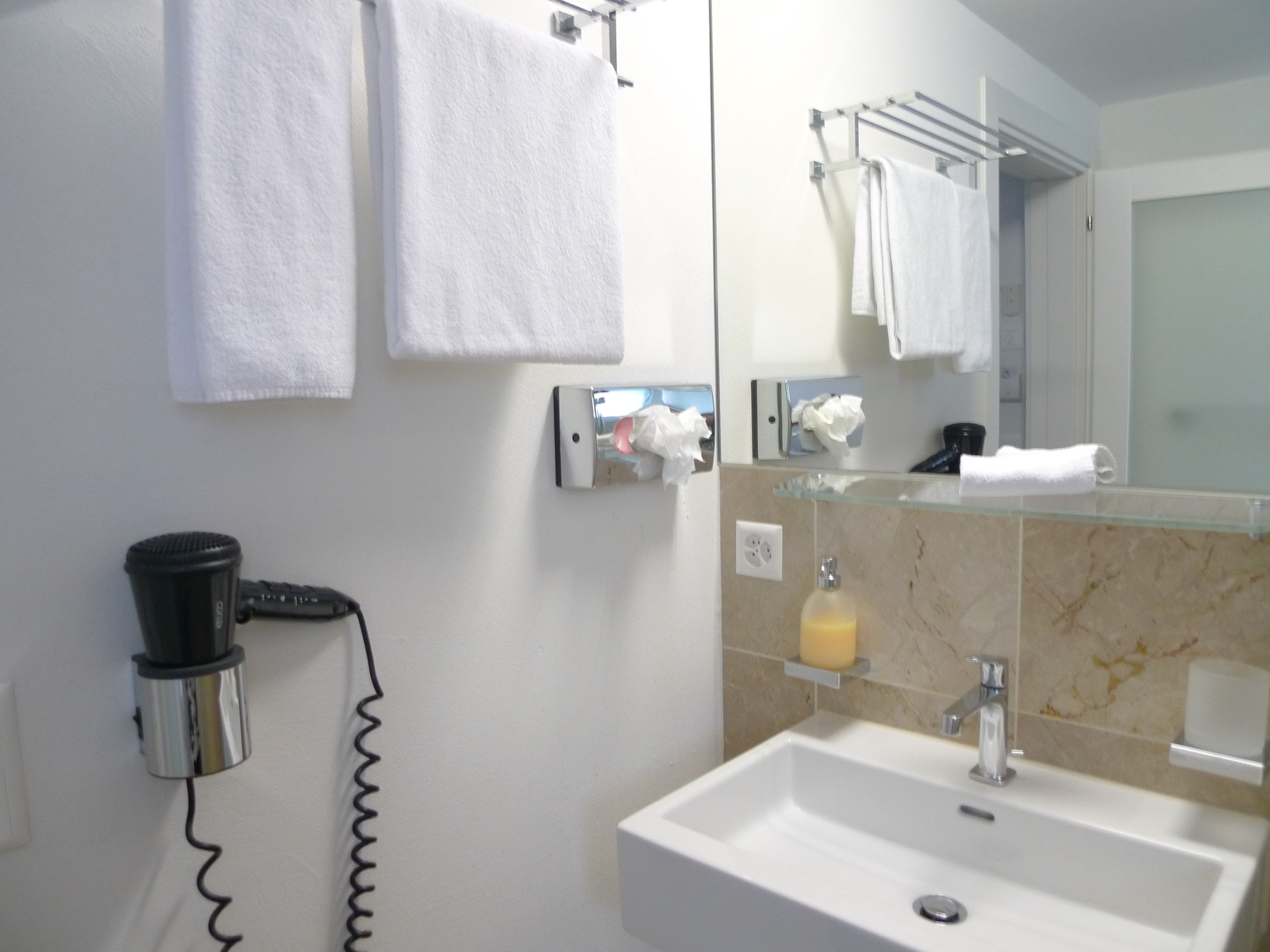A bathroom with a sink, mirror, towel rack, and a hairdryer.
