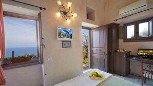 Ein Schlafzimmer mit Bett, Nachttisch, Fenster mit Blick, Wand-Fernseher und Deckenventilator.