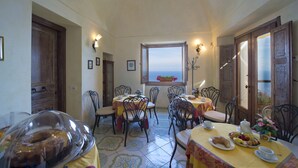Ein Essbereich mit Tischen und Stühlen, ein Fenster mit Blick und ein Buffet mit Speisen.