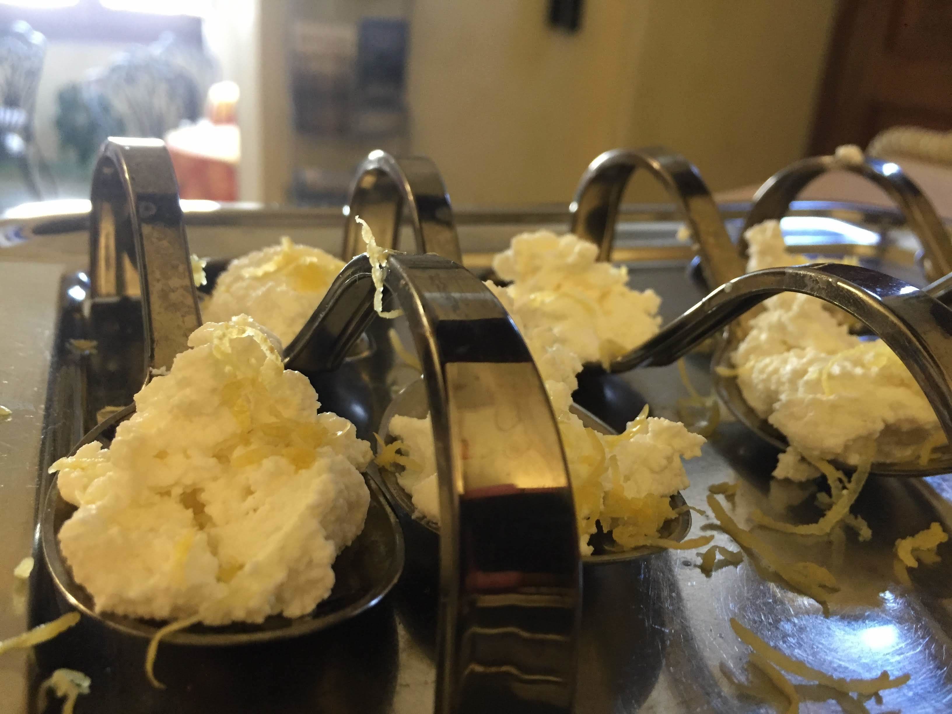 A kitchen with a metal grater and a spoon filled with grated cheese.