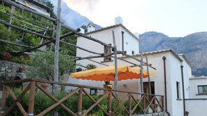 Ein Gebäude mit einer Steinmauer, Holzgerüsten und einem orangefarbenen Sonnenschirm.