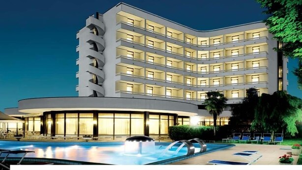 A multi-story hotel with a pool area, outdoor seating, and a well-lit facade. - Hotel Commodore Terme (Montegrotto Terme)