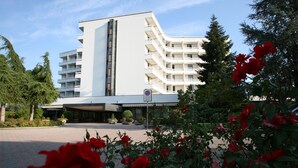 A modern building with a curved facade, multiple balconies, and a no parking sign. - Hotel Commodore Terme (Montegrotto Terme)